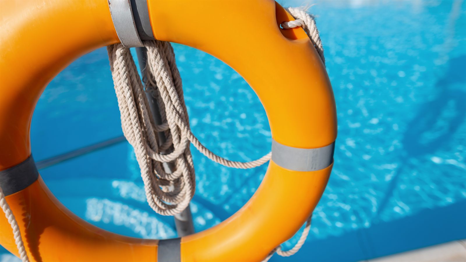 Boia salva-vidas à beira de uma piscina azul ao pôr do sol