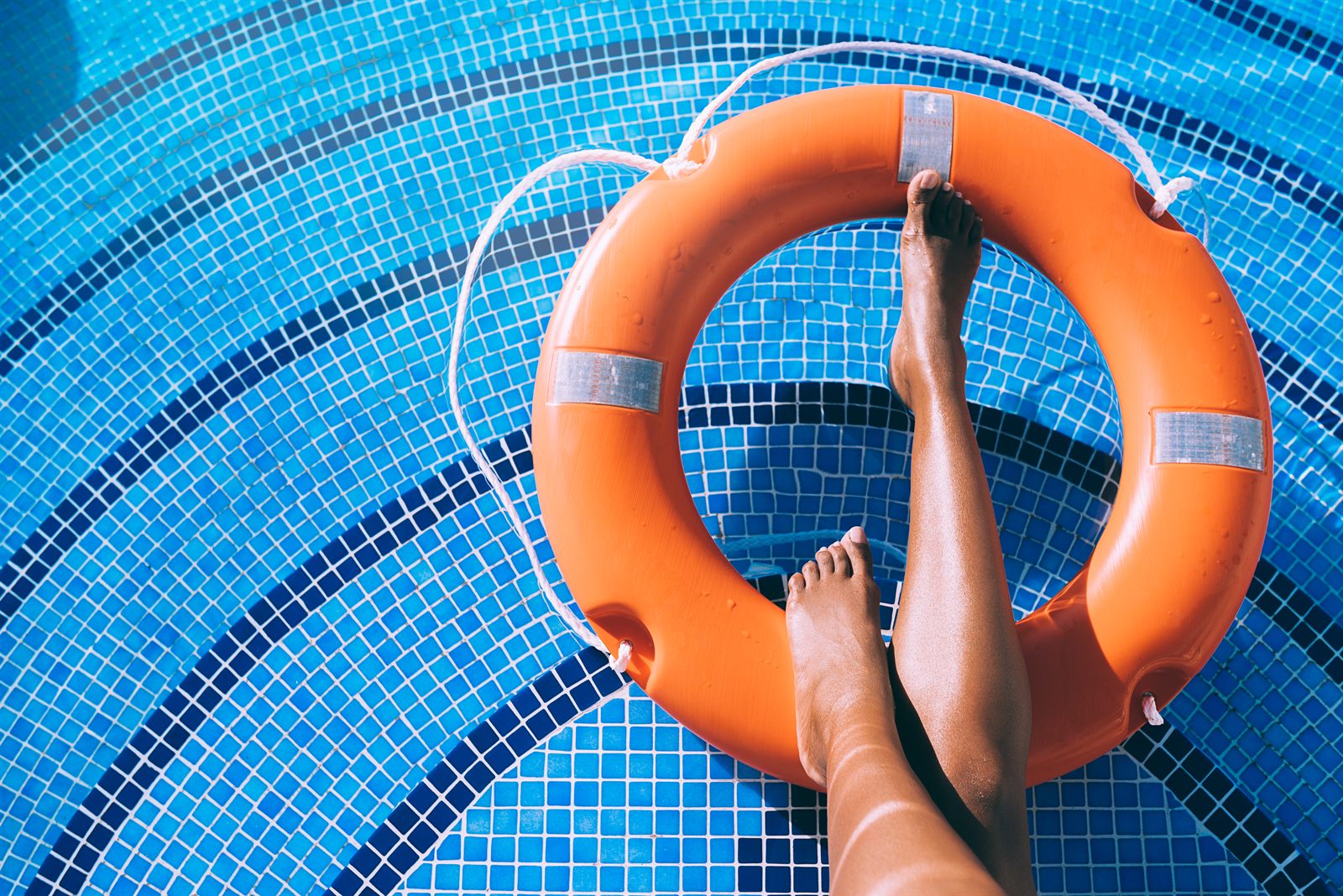 Pessoa relaxando na borda da piscina com boia salva-vidas