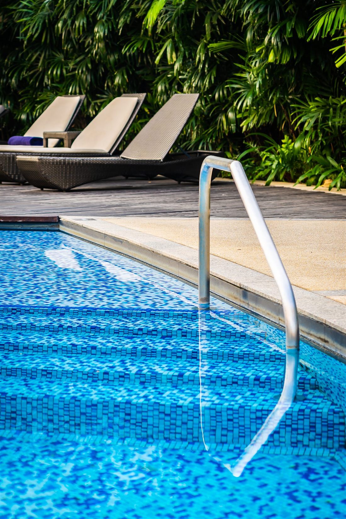Piscina externa de área de lazer com espreguiçadeiras e guarda-sol